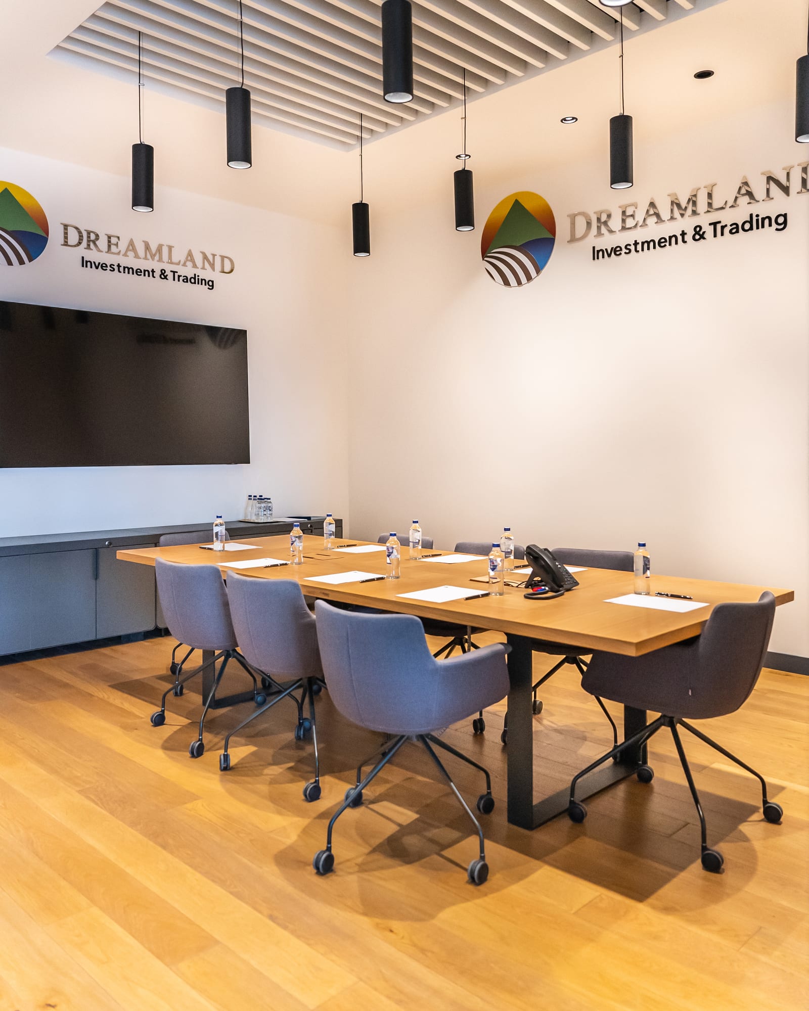 Dreamland toplantı odası: sarkıt aydınlatmalar altında uzun meşe masa, duvarda Dreamland markası